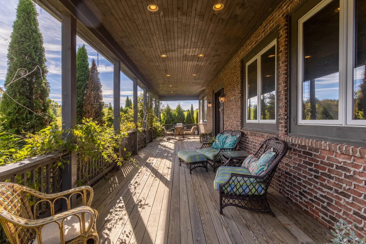 A tranquil wooden deck with woven chairs, surrounded by lush plants and greenery, and views extending toward a distant seating area. The space feels peaceful, inviting guests to relax and enjoy the natural surroundings—ideal for morning coffee, reading, or soaking in the mountain air.