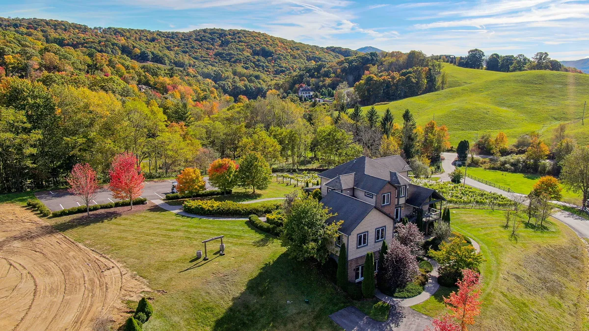 The exterior of the villa is showcased, surrounded by colorful trees and a peaceful landscape. The home’s grand presence is balanced by the natural beauty of rolling hills, gardens, and open spaces inviting exploration.