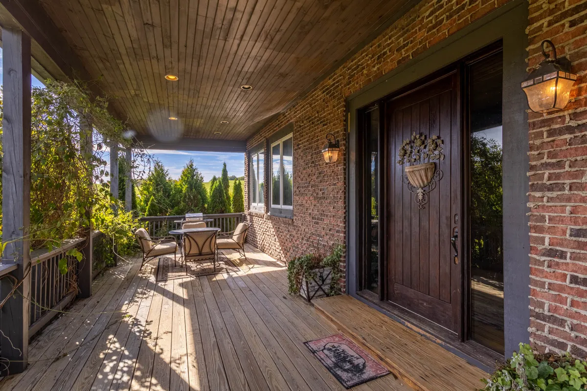 An inviting outdoor seating arrangement next to a wooden door with intricate design, surrounded by lush greenery. The setup encourages relaxing mornings, social gatherings, or quiet moments immersed in nature.
