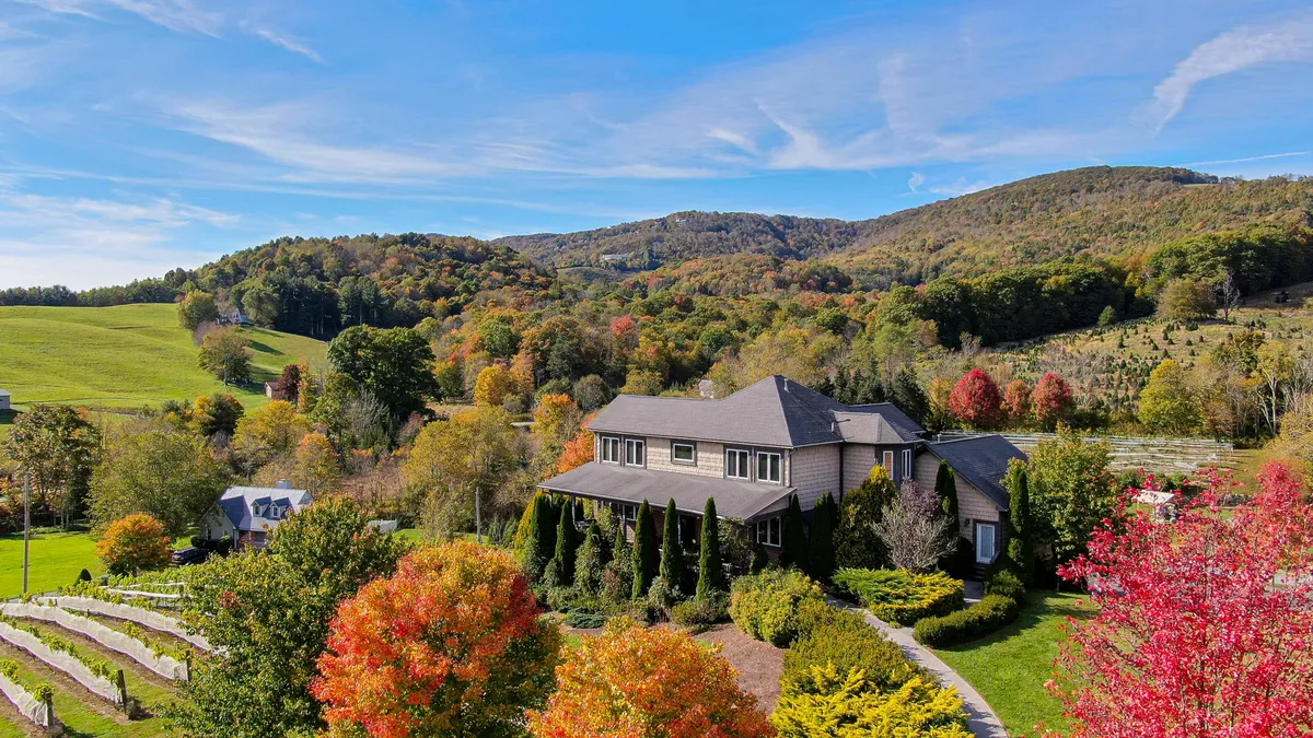 This image shows the villa’s exterior surrounded by colorful trees and rolling hills, providing a glimpse of the home’s natural setting. The lush landscape and expansive yard evoke a sense of space for outdoor activities and gatherings.