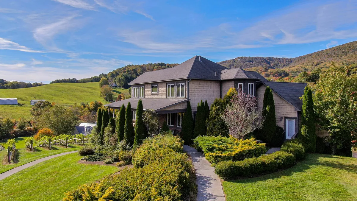The image showcases the Tuscan-inspired Banner Elk Winery Villa, an elegant estate nestled amidst lush garden pathways and rolling hills. The expansive exterior highlights the villa’s grandeur, with manicured grounds perfect for outdoor gatherings, and panoramic views of the surrounding countryside, evoking a serene and inviting atmosphere.